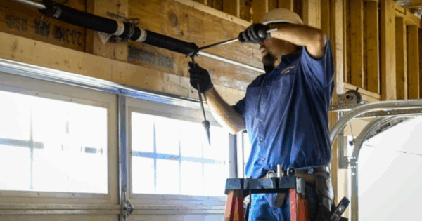 Garage door technician adjusting a garage door spring with tools.